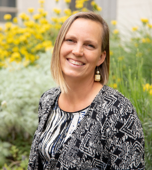 Close up of a woman smiling in front of flowers outside